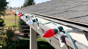Installer securing a strand of lights while traversing a rooftop